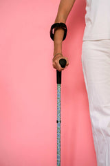 Person holding a cane against a pink background