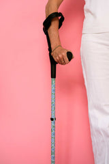 Person holding a walking stick with a pink background