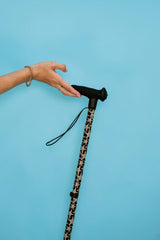 Hand holding a walking stick with a starfish print pattern against a blue background