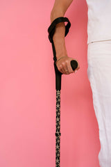 Person holding walking crutches with a leopard starfish print pattern against a pink background