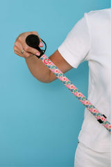 Person holding a walking stick in a funky pattern with a floral strap against a blue background