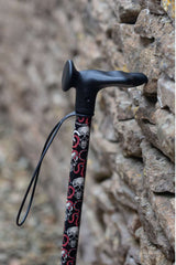 Top of black walking stick with a skull and snakes design showing ergonomic moulded handle