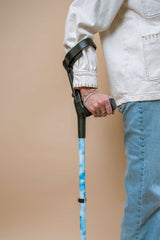 Person holding a blue crutch against a beige background