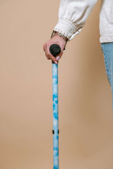 Person holding a blue walking cane against a beige background