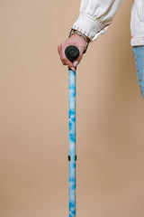 Person holding a blue walking cane against a beige background