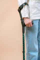 Person holding a walking stick with a beige background