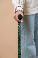 Person holding a green and black cane against a beige background