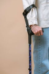 Person holding a purple butterflies crutch against a beige background