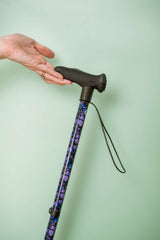 Cane with purple pattern held by a hand against a light green background