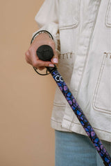 Person holding a floral-patterned walking stick against a beige background
