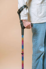 Person holding a colourful leopard print cane with a beige background