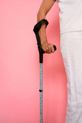 Person holding a walking cane against a pink background