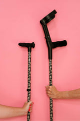 Two crutches with starfish print grips against a pink background