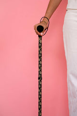 Person holding a patterned funky star print walking stick fish against a pink background