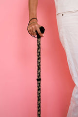 Person holding a patterned cane against a pink background