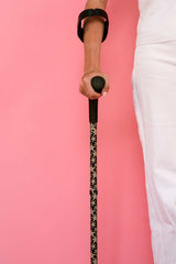 Person holding a cane with a starfish print pattern against a pink background