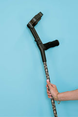 Hand holding a black and starfish print cane against a blue background