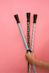 Three floral-patterned sticks held against a pink background