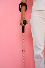 Person holding a funky patterned crutch with a pink background