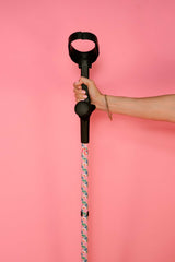 Hand holding a black handled crutches with floral pattern against a pink background
