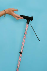 Cane with floral pattern handle held by a hand against a blue background