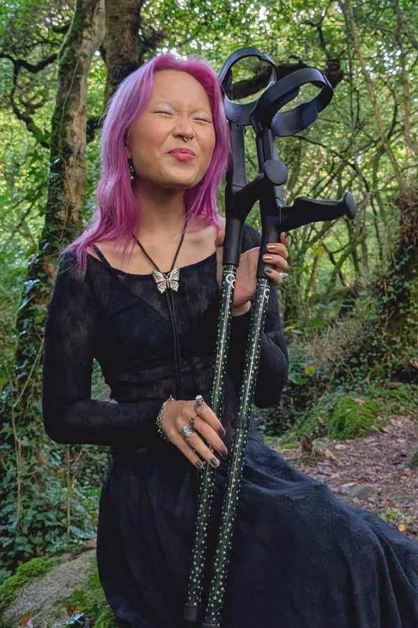 Person holding dark green crutches covered in gold stars from cool Crutches