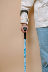 Person holding a blue crutches against a beige background