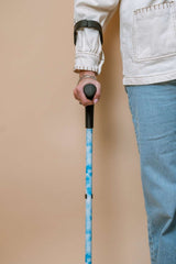 Person holding a blue walking crutch against a beige background