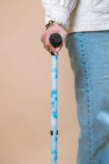 Person holding a blue cane against a beige background