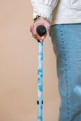 Person holding a blue walking stick against a beige background