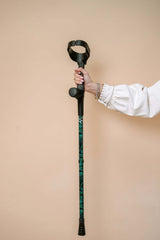 Hand holding a walking cane against a beige background