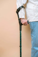 Person holding a walking cane against a beige background
