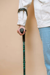 Person holding a walking cane with a beige background