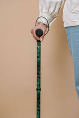 Person holding a green walking cane against a beige background