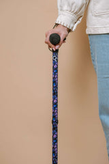 Person holding a walking cane with a patterned handle against a beige background