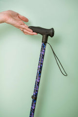Cane with purple pattern held by a hand against a light green background