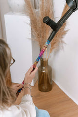 Person holding a colourful leopard print crutches with a minimal background