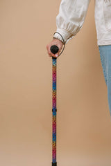 Person holding a colorful walking cane against a beige background