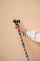 Colourful walking stick held by a person against a beige background