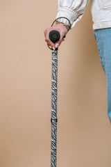 Person holding a zebra-striped cane against a beige background