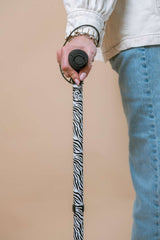 Person holding a zebra-patterned cane against a beige background