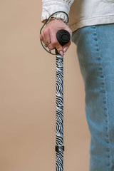 Person holding a zebra funky pattern walking stick against a beige background