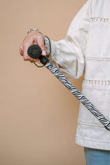 Person holding a leash with zebra pattern against a beige background