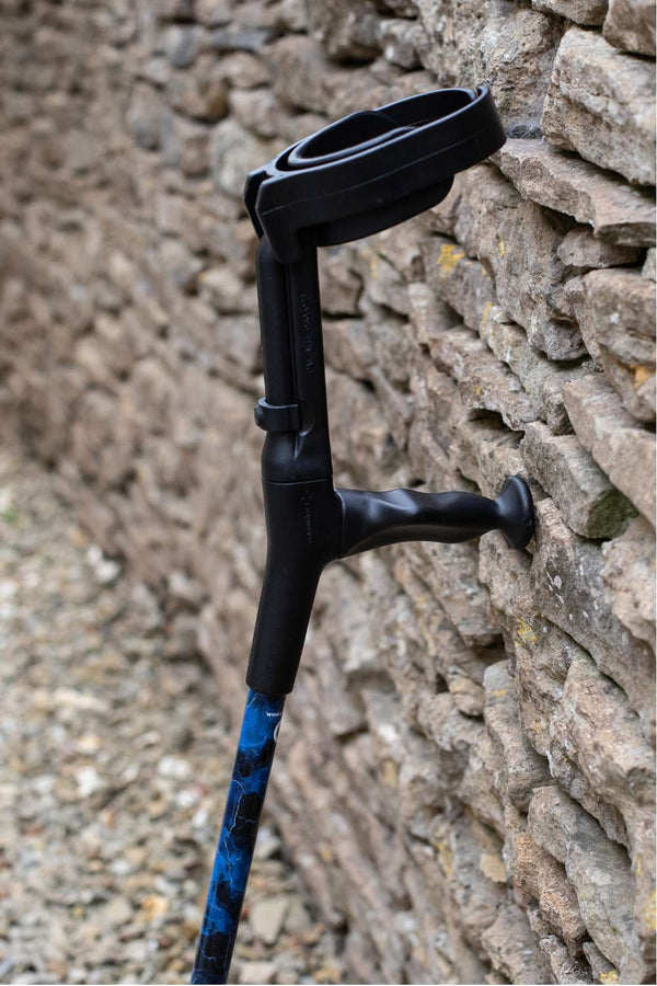 The top of a crutch designed with deep ocean blues and streaks of gold lightning showing the moulded handle and cuff 