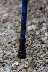 The bottom of a walking stick with a blend of deep ocean blues and electric gold lightning streaks showing the ferrule