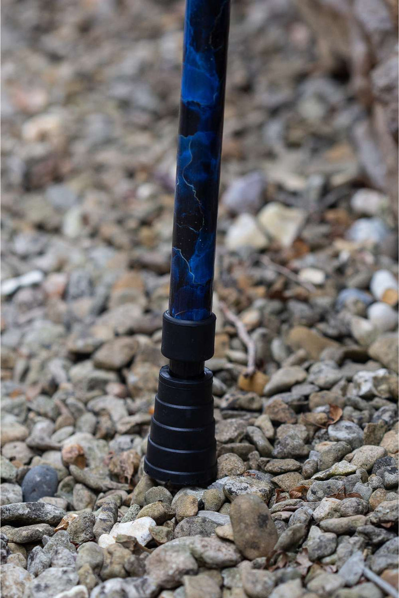 The bottom of a walking stick with a blend of deep ocean blues and electric gold lightning streaks showing the ferrule